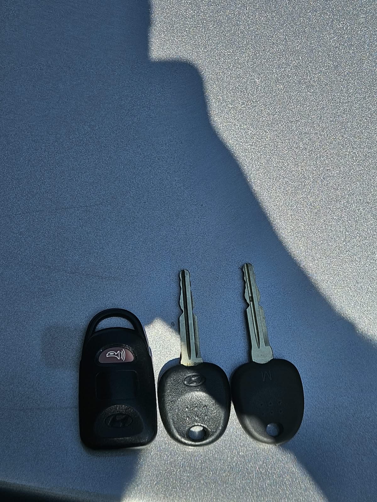 Two Hyundai keys and one remote fob laid on the car bonnet